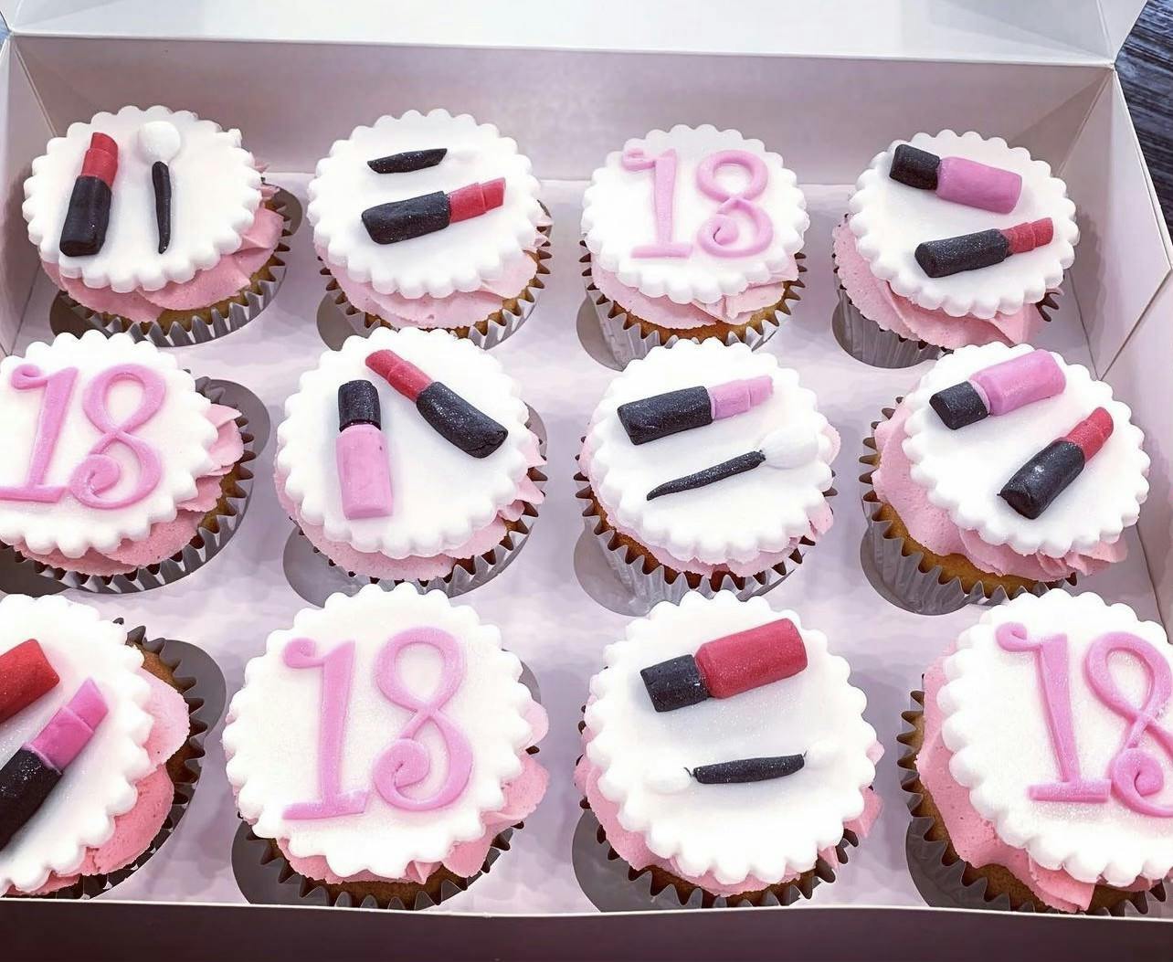 White and pink cupcakes for an eighteenth birthday with fondant lipstick and beauty products on top