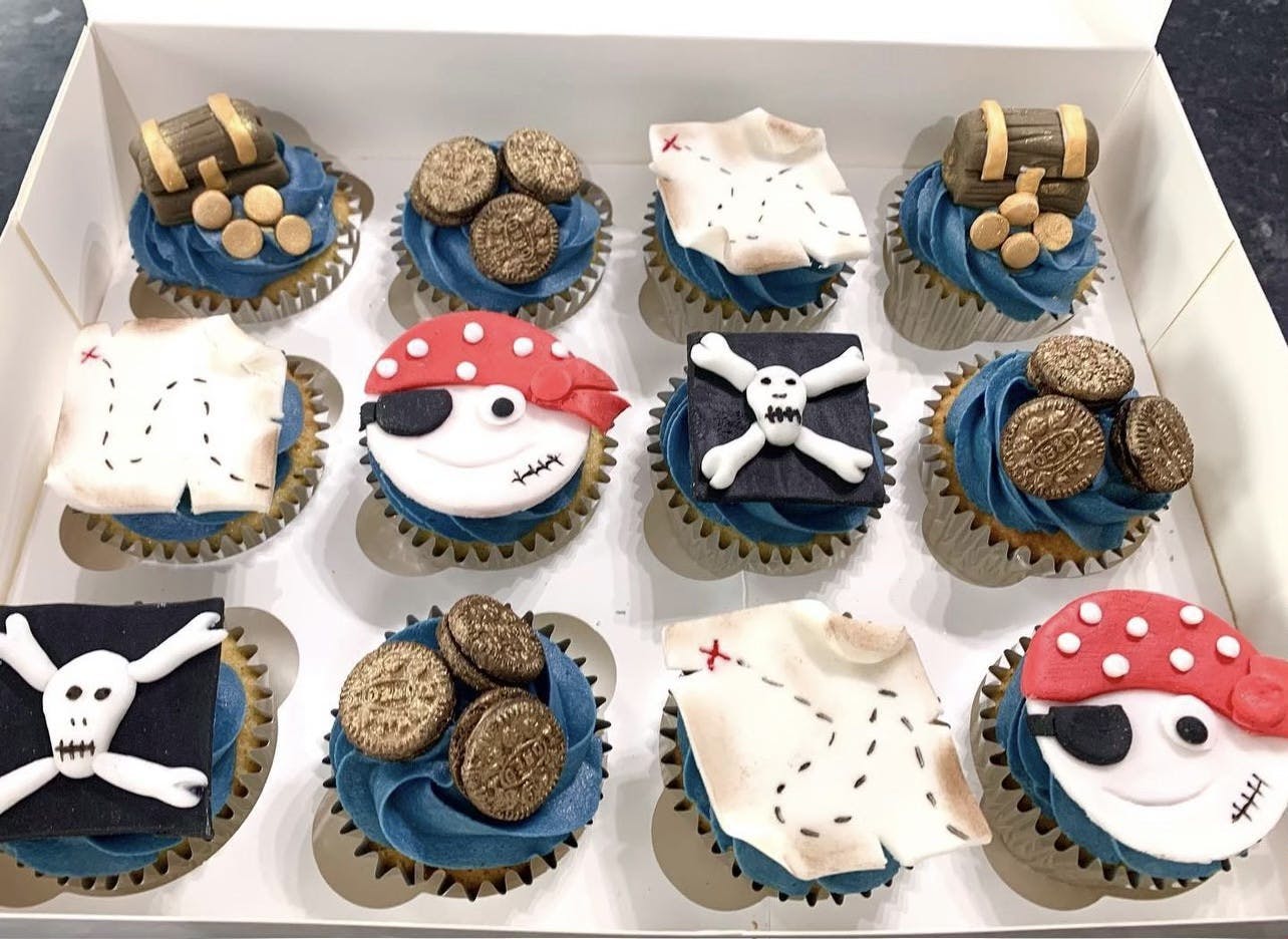 Dark blue iced cupcakes with pirate faces, treasure maps, treasure chests and gold oreo treasure