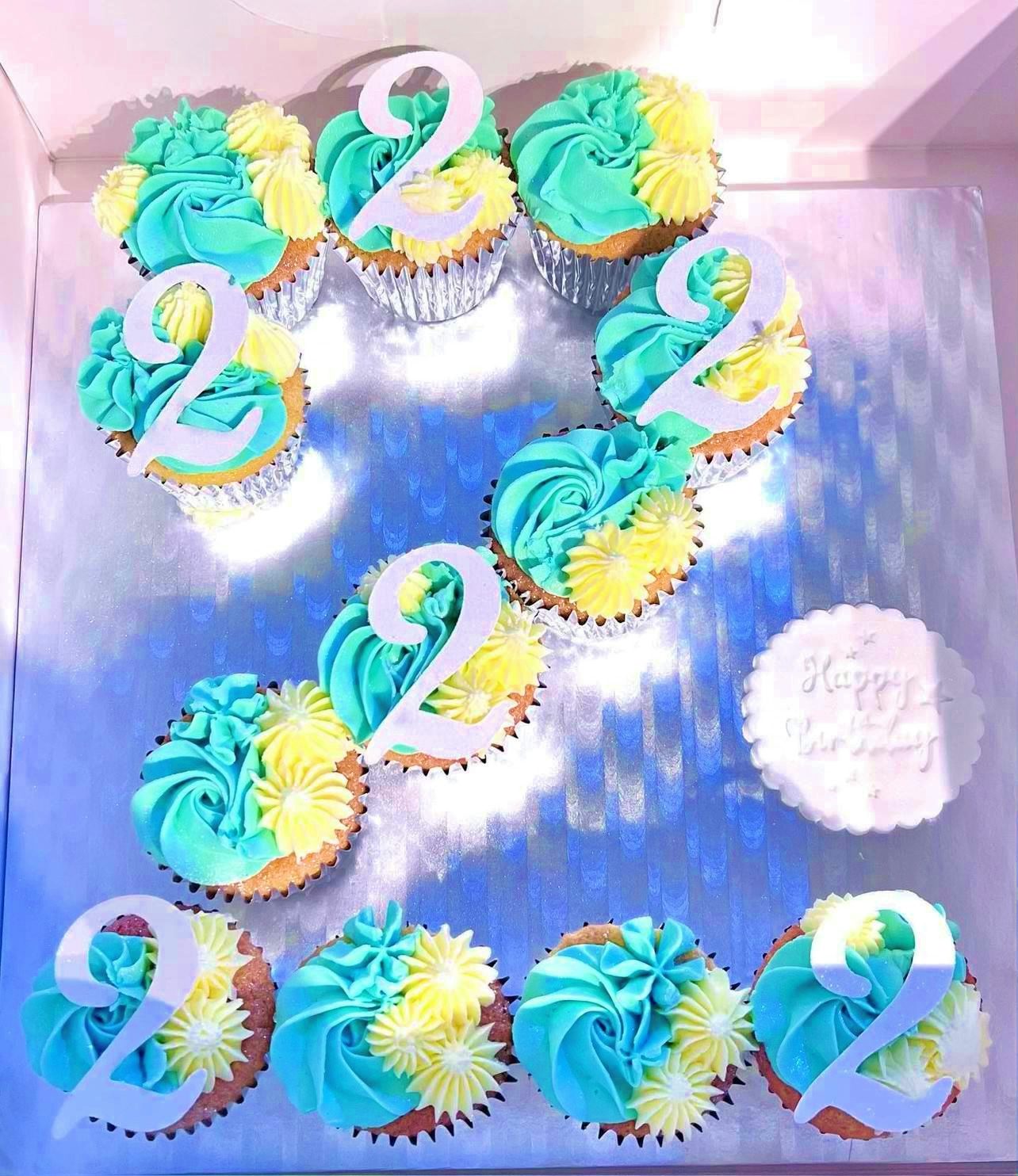 Blue and yellow cupcakes arranged in the shape of the number two