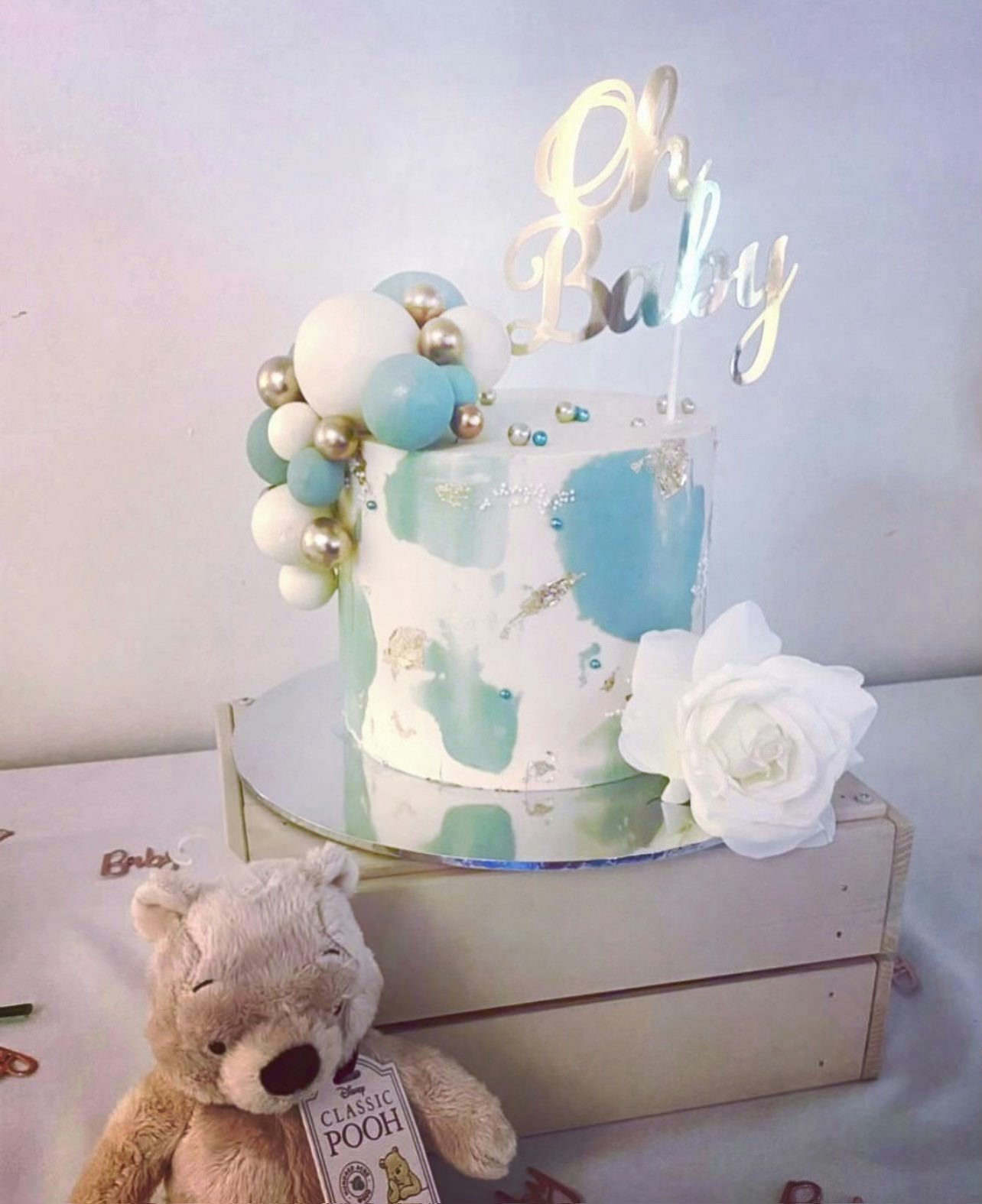 Blue and white watercolour-styled cake with a teddy bear next to it