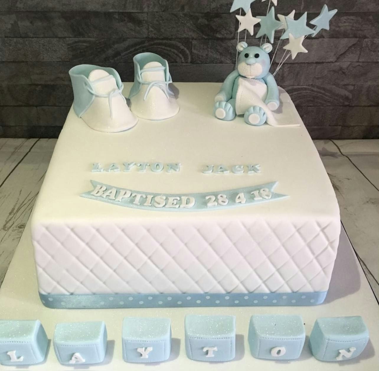 A white and light blue baptism cake with baby shoes