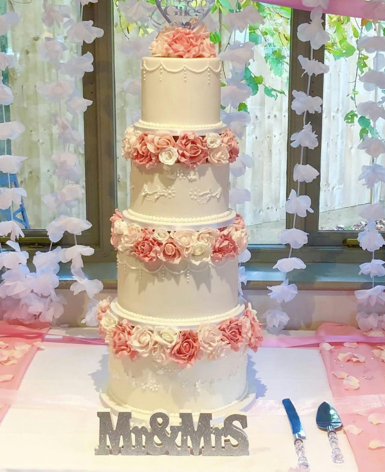 White and cream wedding cake with white and pink flowers and cake pearls