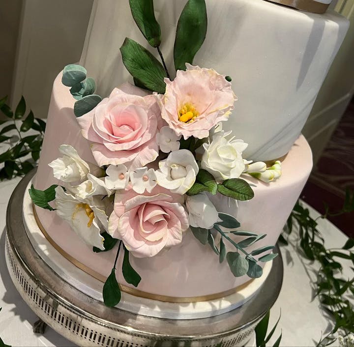 Close-up white wedding cake with flowers and a ring of leaves surrounding